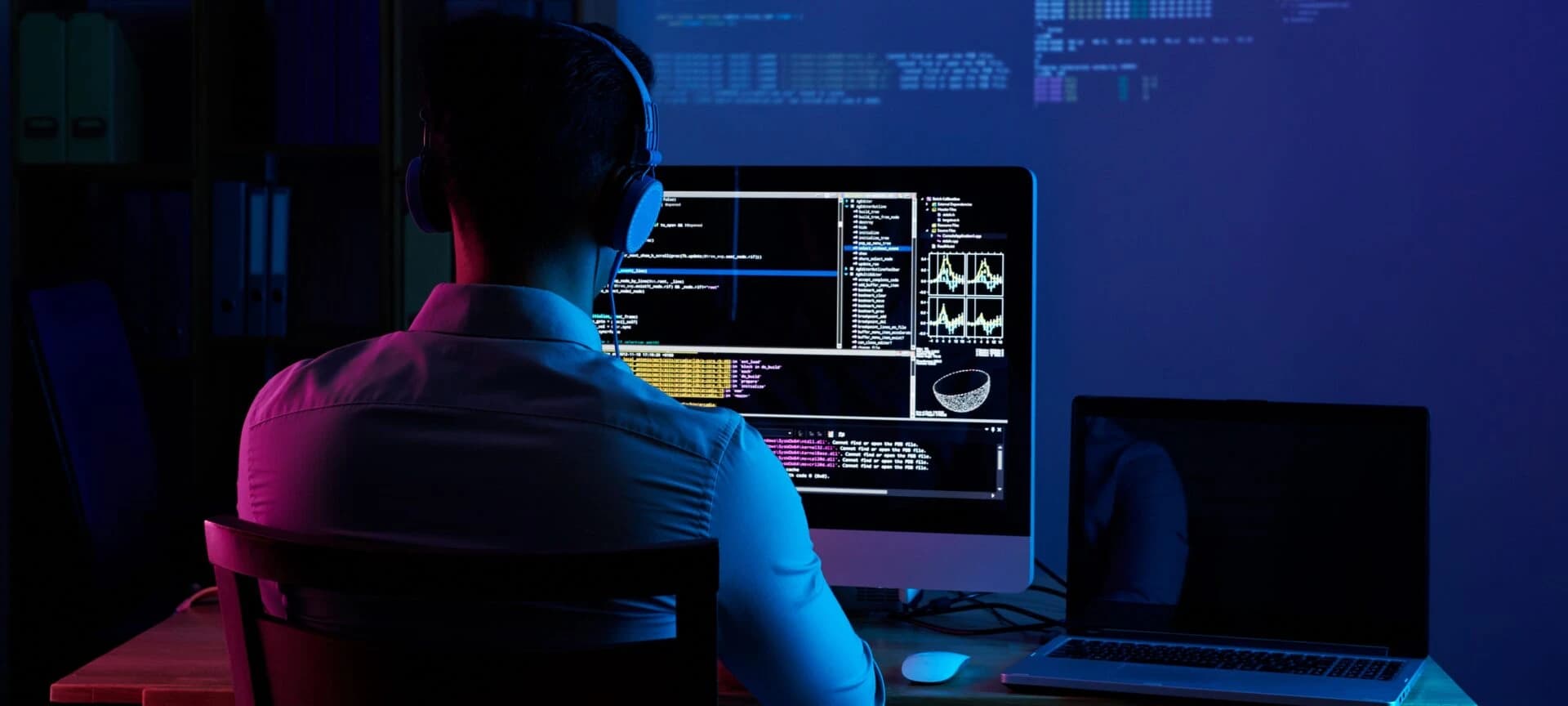 Developer with headphones writing code at a monitor, representing full stack web application development