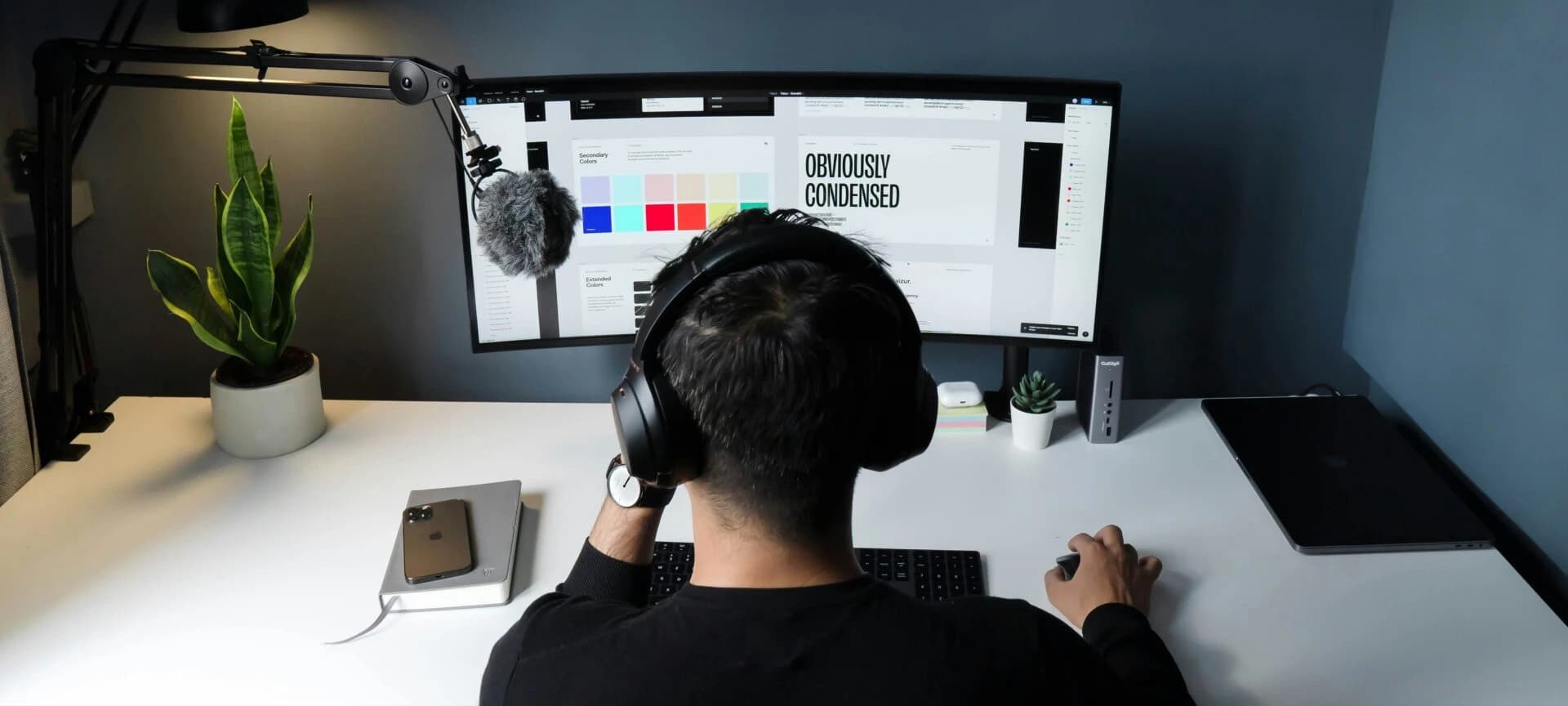 Designer with headphones working on an interface layout and color palette, representing UI/UX design services