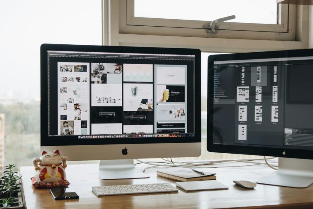 Two monitors displaying website page layouts, representing website development by Aaga