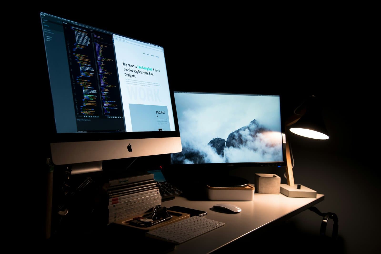 Desk with a computer showing website code next to a second monitor, representing website development